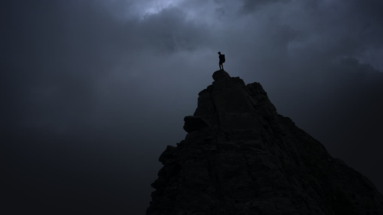 Hiker on Mountain Summit During Storm