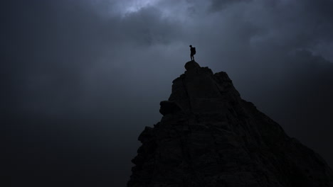 hiker on mountain summit during storm