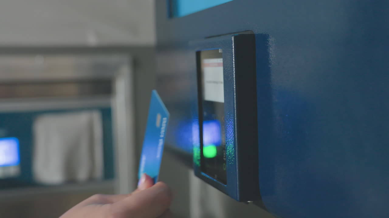 Cashless payment panel on wall in modern laundromat as customer hand taps card on reader then removes it, contactless transaction under blue light, close view of machine, glossy reflection