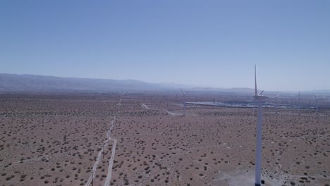 slow drone push-in overlooks desert with windmills on the side