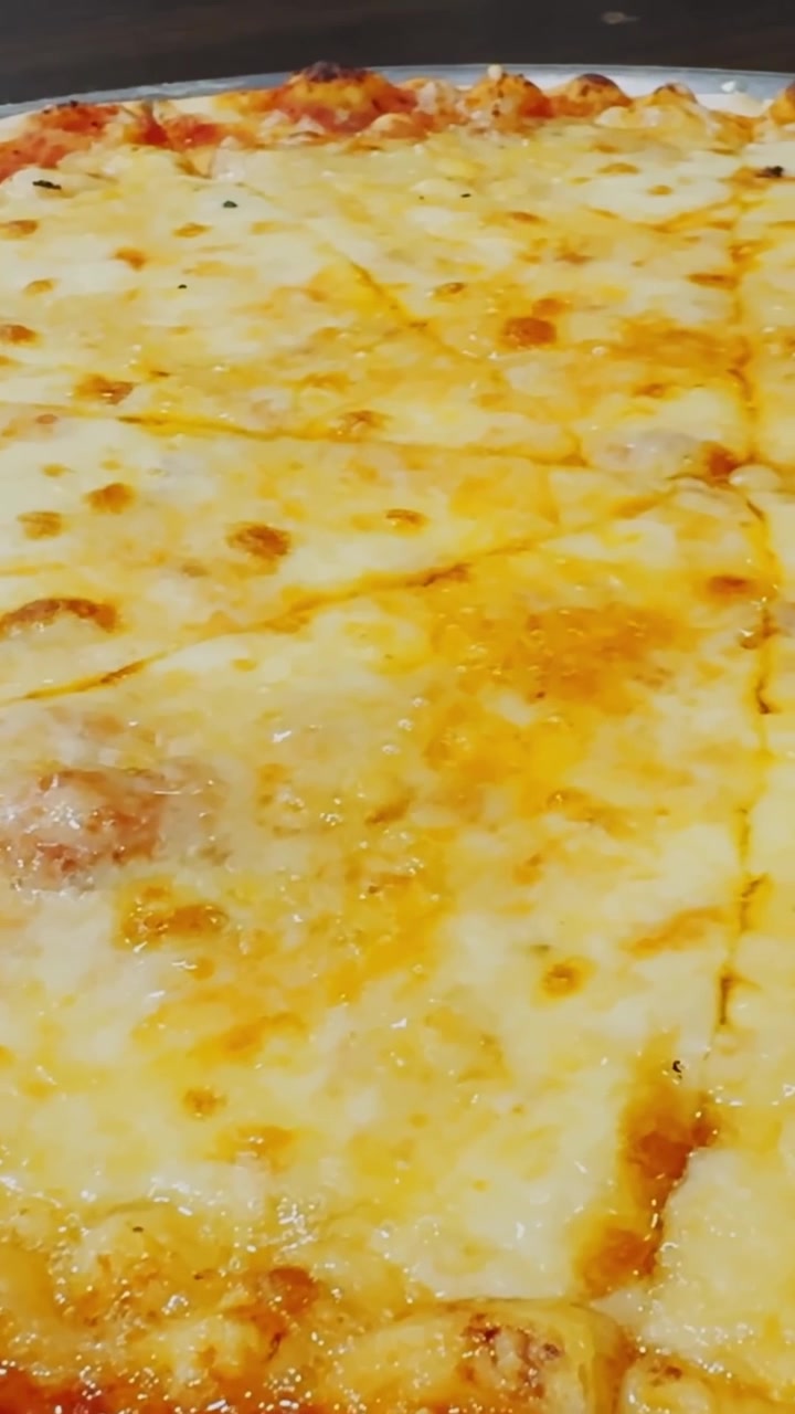Primo piano di pizza al formaggio con mozzarella fusa, salsa di pomodoro e crosta dorata e cotta, che mostra cibo caldo da ristorante pronto per essere servito