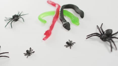 close up view of halloween spiders and snakes toys against grey background