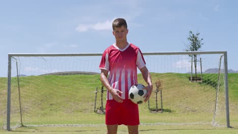 soccer player standing with the ball on the field