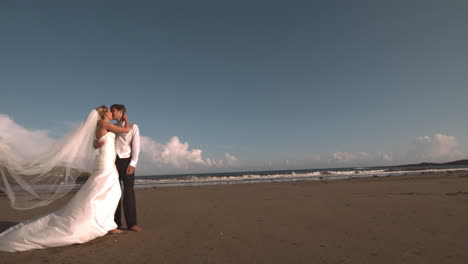 Feliz-Pareja-Nupcial-Besándose-En-La-Playa