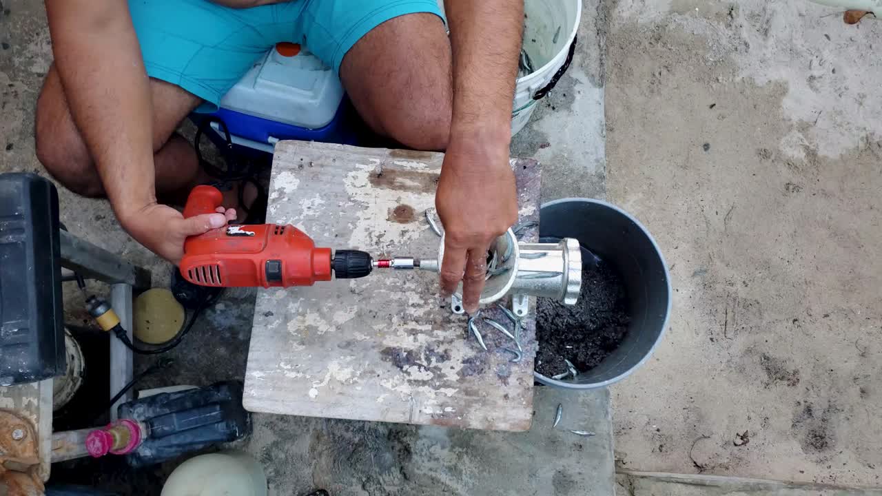 Tampilan atas: tangan pria menggiling umpan untuk memancing secara tradisional, budaya Latin