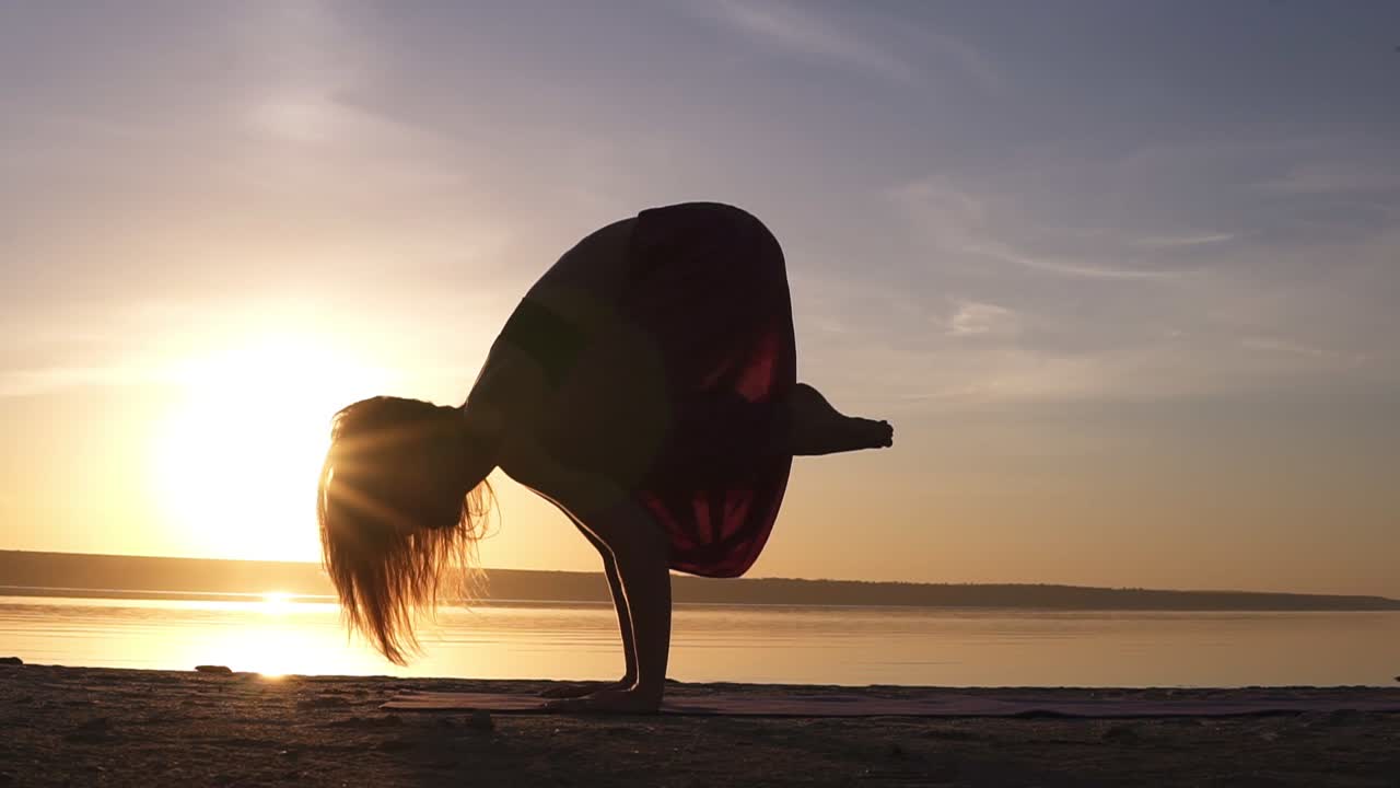 Yoga bakasana crane pose by woman in silhouette with haze sunset sky on background