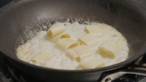 Pasta-simmers-in-a-white-sauce-within-a-pan,-combining-to-create-a-creamy-dish