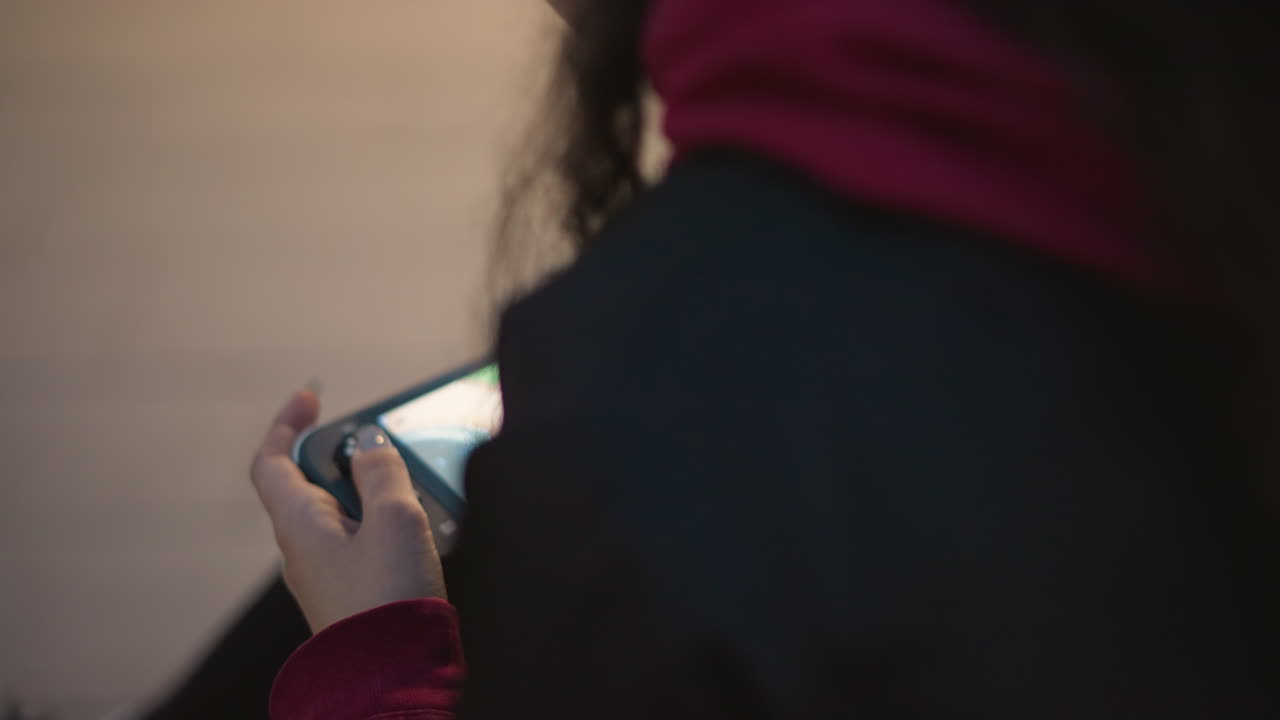 Intense Mobile Game Session With Focused Woman, Asian Female Engrossed In Phone During Evening At Park Bench, Close View Of Asian Woman Concentrating On Her Phone While Playing Game Outdoors At Dusk