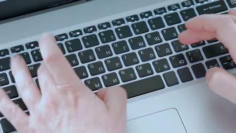 male hands are typing text on a laptop keyboard, top view, close-up