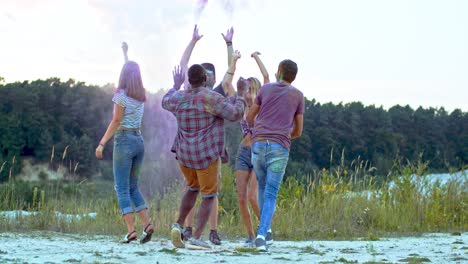 alegre joven compañía de razas mixtas de gente bailando y divirtiéndose fuera del festival holi con pinturas coloridas