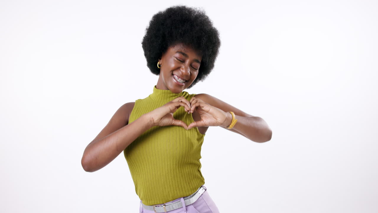 Una donna sorridente con capelli afro che forma un cuore con le mani
