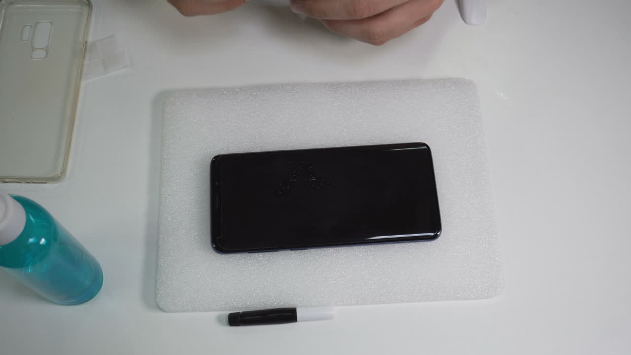 남자는 스프레이를 뿌리고 스마트폰 화면을 청소한다