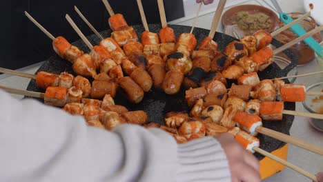 Grupo-De-Amigos-Preparando-Suki-Satay-De-Barbacoa-Y-Asándolos-Sobre-Una-Sartén-Caliente