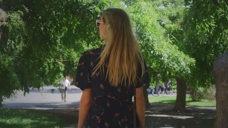 Ukrainian-Woman-Model-Walks-in-Tree-Lined-Shaded-Park-on-Sunny-Morning,-Slow-motion-Handheld