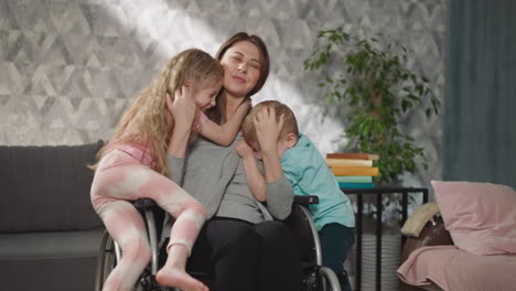 Loving-children-come-to-hug-mother-sitting-in-wheelchair