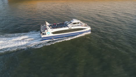 aerial view of a ferry crossing new york city's east river. shot at sunset during the autumn of 2024 in 4k.