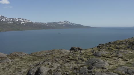 volando más allá de la meseta de roca volcánica para revelar el fiordo reyðarfjörður en islandia