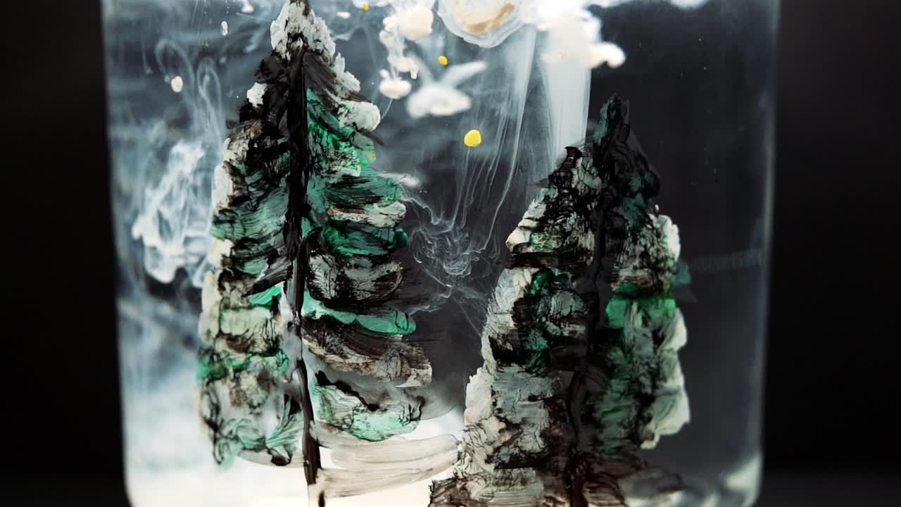 White paint floating in water tank with pine tree drawing inside. Stable shot with the Sony a7iii.