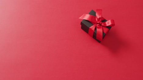 Black-gift-box-with-red-ribbon-on-red-background-with-copy-space