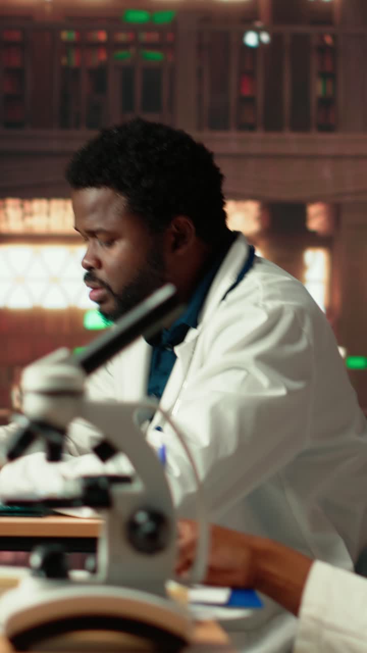 Scienziato/a afroamericano/a al lavoro in laboratorio con un microscopio