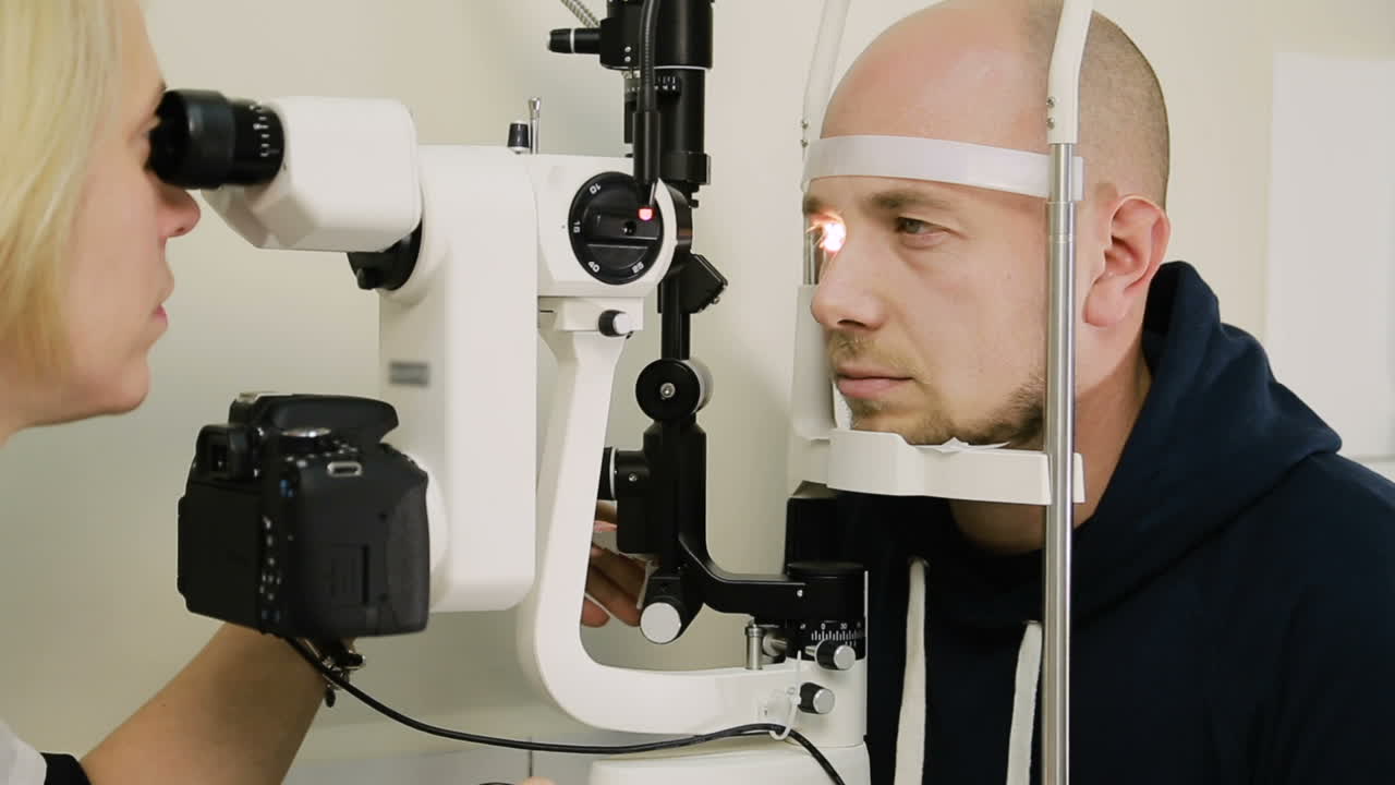 Man having eye test. Female optometrist examining mans eyes through slit lamp in clinic