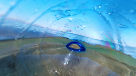 una botella de plástico descartada descuidadamente flotando en el océano y contaminando el medio ambiente, como se ve desde el interior de la botella