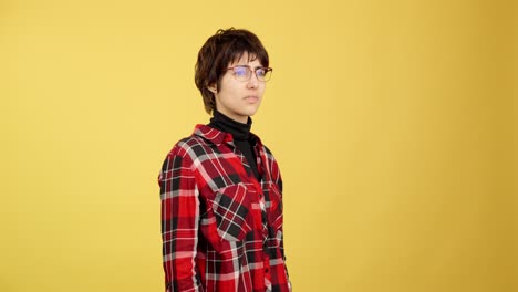 young person with confused expression adjusting glasses on yellow background