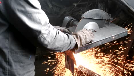 cutting of metal. closeup men's hands cutting metal with a circular saw. sparks fly to the side.