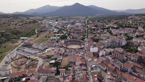Spanish-San-Marti-n-de-Valdeiglesias-municipality-aerial-view-rising-away-from-legendary-bullring-and-mountain-landscape