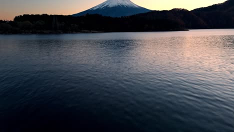 esta fascinante grabación de dron comienza con un primer plano de las aguas tranquilas del lago kawaguchi, revelando los tonos dorados de una puesta de sol de otoño en el monte fuji.