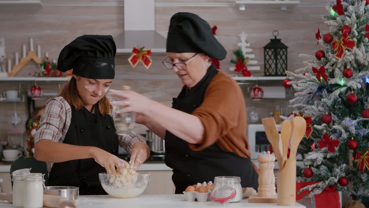 nieto con delantal preparando galletas de invierno caseras masa en la cocina culinaria