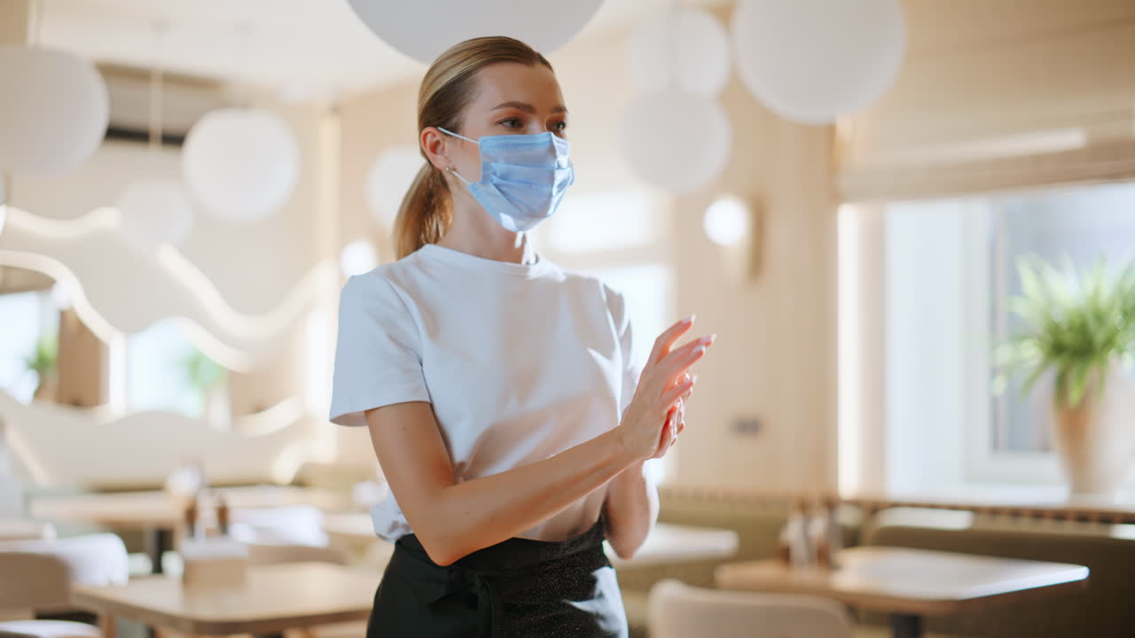 Cameriera che si disinfetta le mani in un moderno ristorante luminoso, primo piano