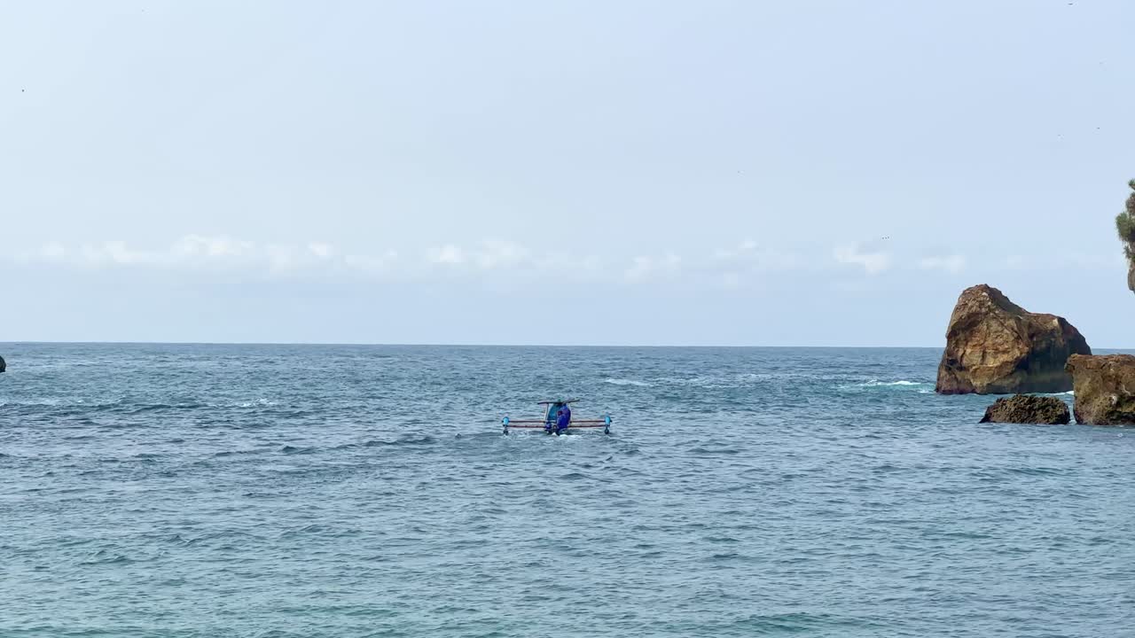 Fisherman in a Traditional Boat on the Ocean near Rocky Coastline