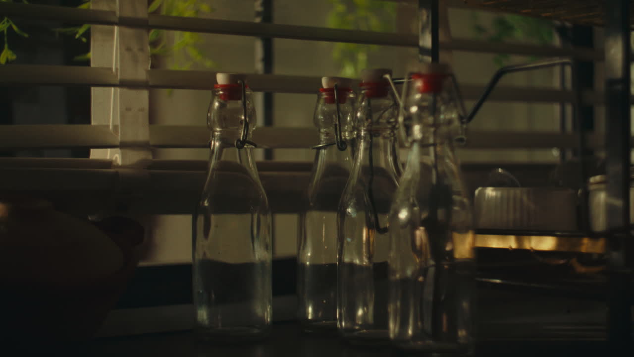 Bottles with water on a kitchen counter by a window, warm sunlight creating a cozy feel