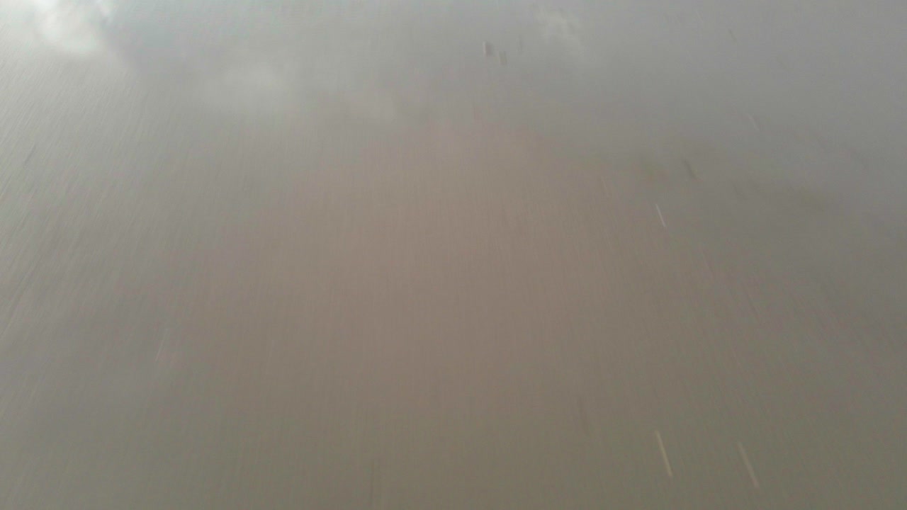 un dron de baja altitud vuela hacia el mar en hvide sande, mirando directamente hacia abajo y lentamente inclinándose hacia arriba para revelar el océano expansivo a medida que avanza, capturando una dramática vista costera en un día de tormenta