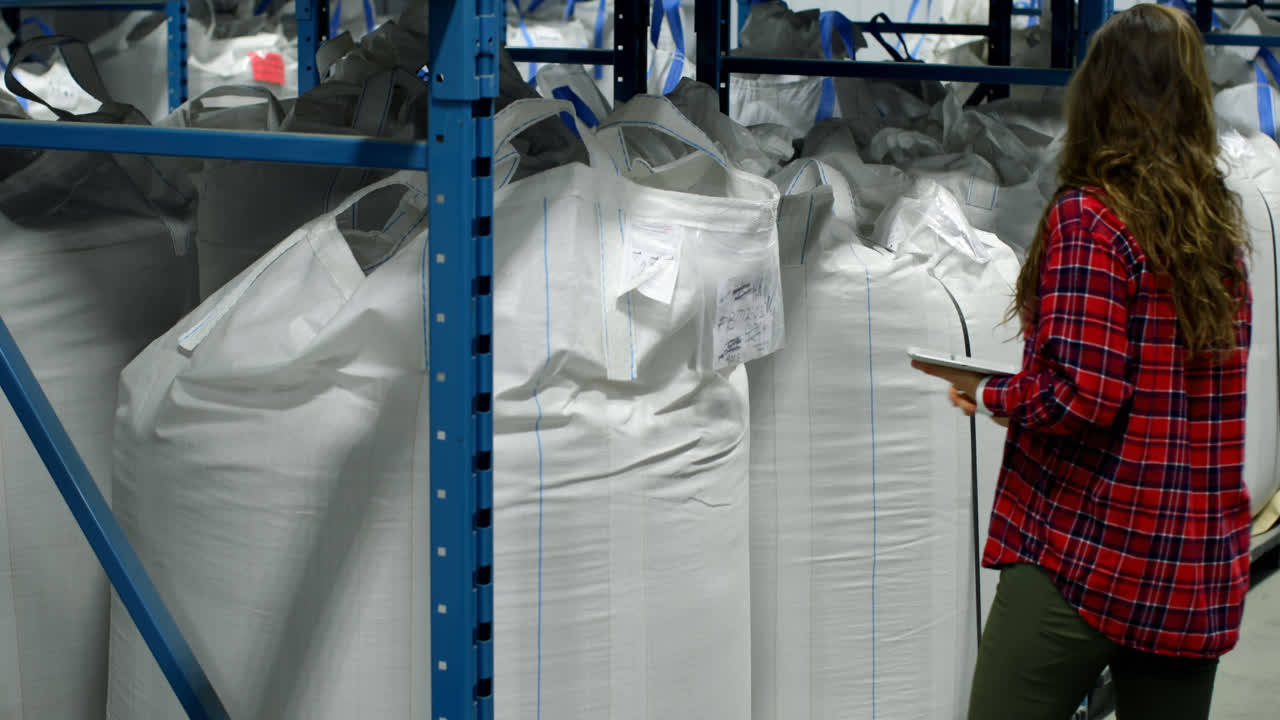 vista lateral de una trabajadora caucásica comprobando las existencias en el almacén 4k