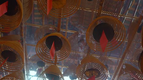 cinematic shot of circular incenses attach to the roof burning slowly and diffusing smoke