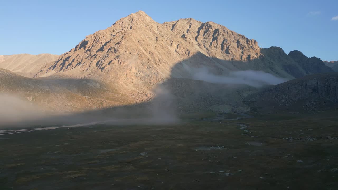 Lonely peak glowing in morning light with mist covering the valley below