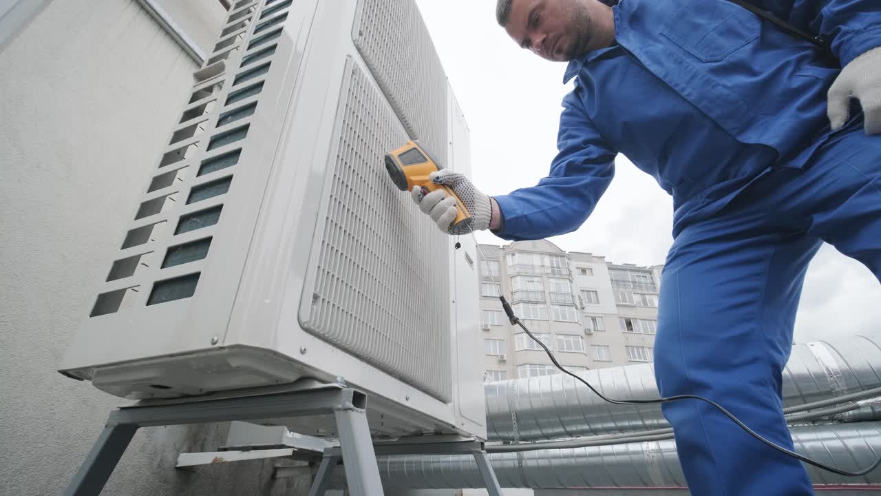 Technician uses a thermal imaging infrared thermometer to check the condensing unit heat exchanger