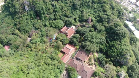 Drone-aerial-view-in-Vietnam-flying-over-Da-Nang-coast-city-marble-mountains-top-view-full-of-trees-and-buddhist-temples-on-a-sunny-day