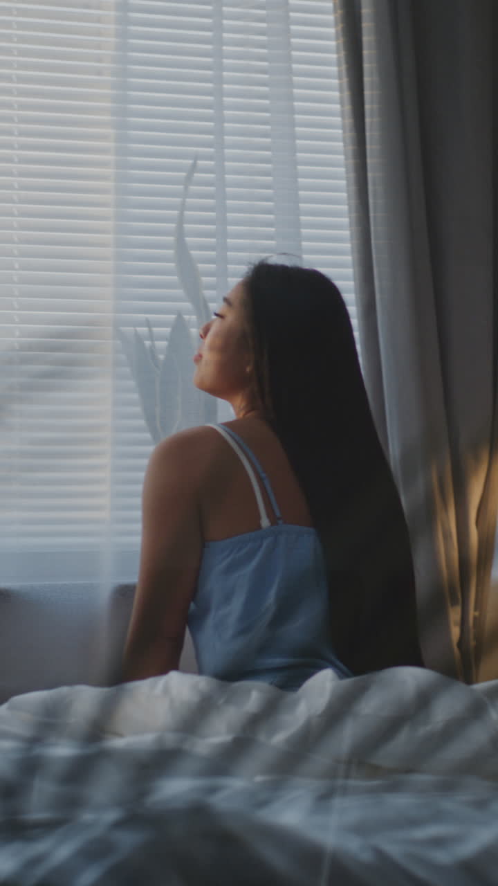 Woman in bed looks out window in morning