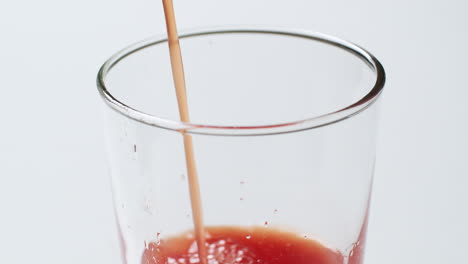 filling a glass with a refreshingly cold tomato juice as it bubbles up to its brim, and dripping some of it on the sides of the glass