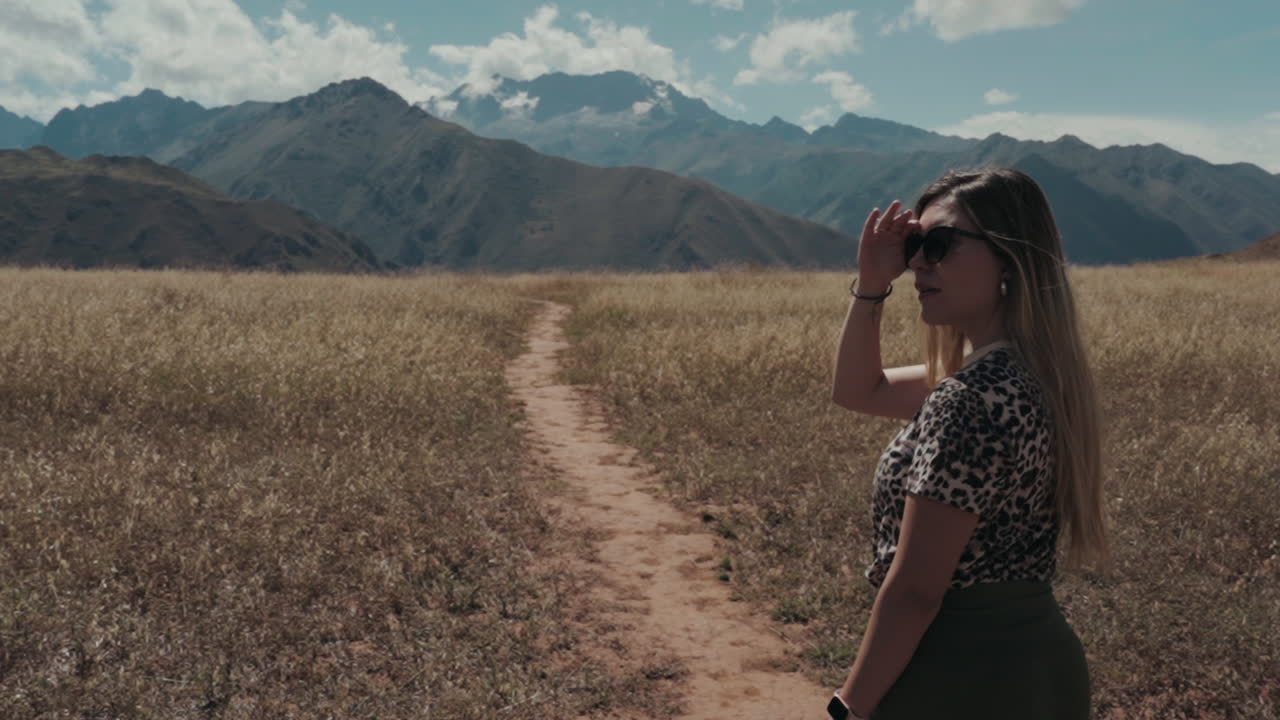 Woman looking at mountains in a vast field
