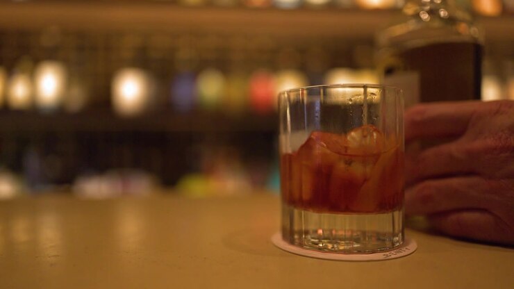 Nærbillede af en negroni-cocktail på en disk med varm bokeh-barbaggrund i Kanazawa