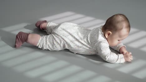 baby lying on her back with sunlight through window on sunny morning