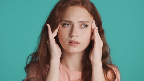 redheaded girl in front of camera on turquoise background.