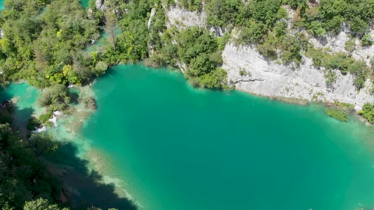 바위와 무성한 푸른 나무가 있는 호수의 오름차순 드론 샷