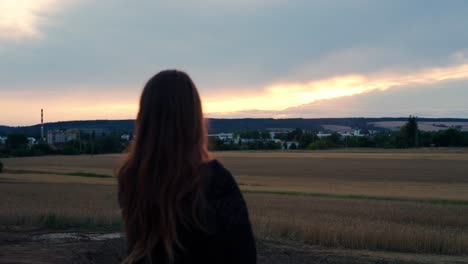 silueta de una mujer mirando hacia el atardecer sobre la ciudad