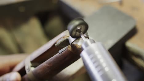 biracial female worker shaping ring using handcraft tools in workshop in slow motion