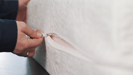 primer plano de manos femeninas abrochando una cremallera en un colchón blanco